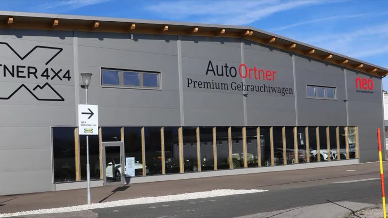 Die Gebrauchtwagenhalle von Auto Ortner: Halle mit den Schriftzügen Ortner 4x4 und Auto Ortner Premium Gebrauchtwagen, Fahrzeuge hinter der Glasfront