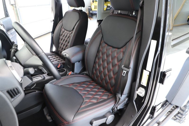 Innenraum eines Jeep Wrangler mit schwarzer Lederausstattung und roter Rautensteppung auf Sitzen und Kopfstützen