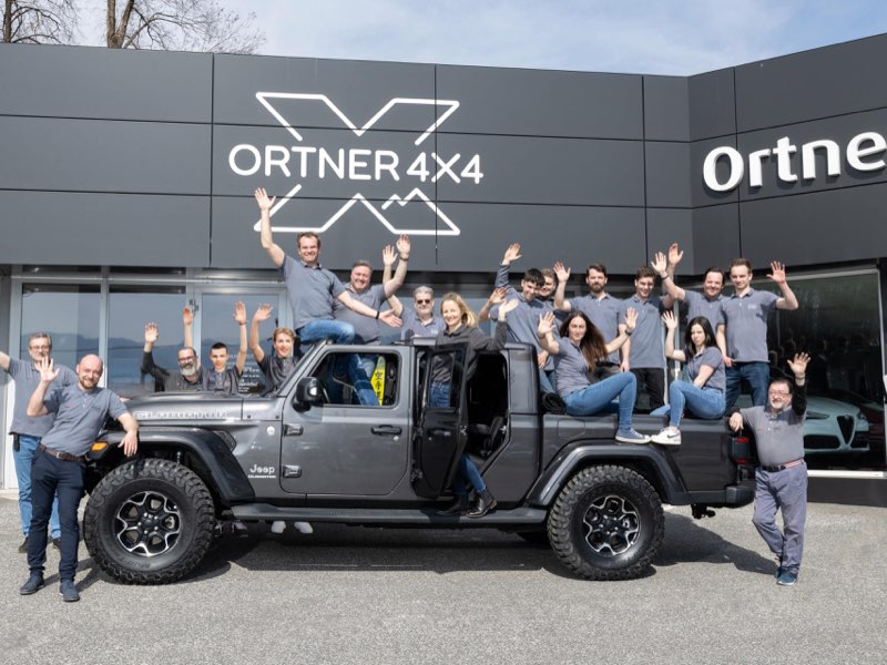 Die Mannschaft von Auto Ortner vor dem Betrieb in Villach, gruppiert um einen umgebauten Jeep Gladiator unter dem Schriftzug Ortner 4x4